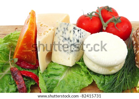 fresh aged french cheeses chops on big cutting board with tomatoes olive oil, rye bread and green chives isolated over white background