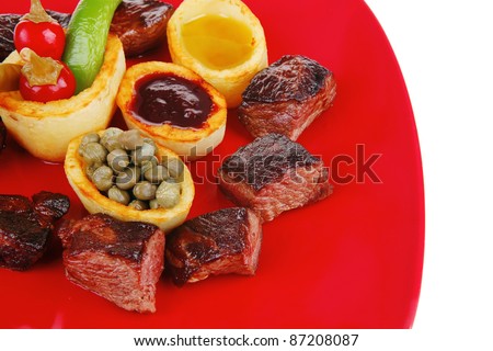 european food: roast beef meat goulash over red plate isolated on white background with tomatoes and dill and bbq sauce