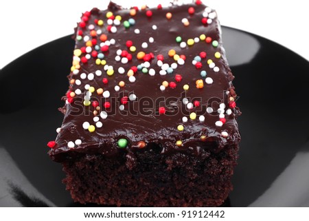 sweet food : chocolate cake coated with chocolate on black saucer isolated over white background