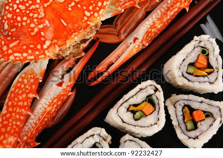 Sushi Maki Roll with Vegetables and Salmon inside . on black dish with boiled crab . Japanese Cuisine