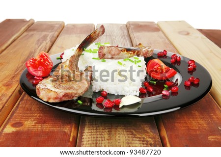 main course: grilled ribs with rice and tomatoes on black dish over wood