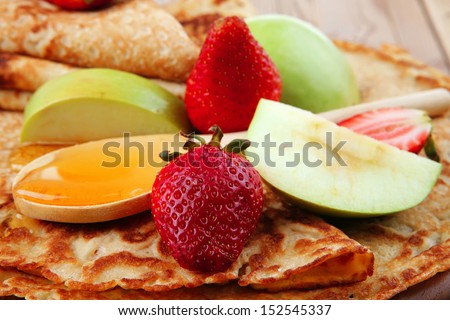 baked and fruits : pancake with honey strawberries and apple on wooden table