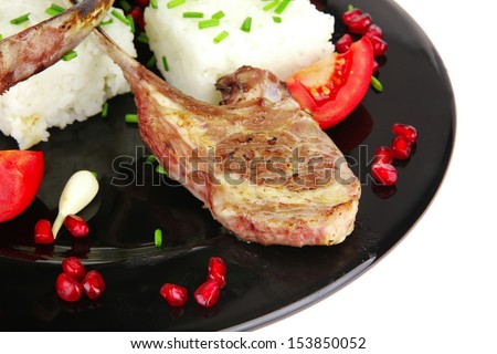 main course: grilled ribs with rice and tomatoes on black dish over white background
