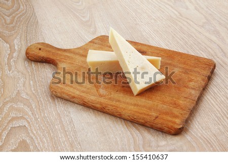 two fresh triangle french delicacy parmesan cheese pieces on wooden cut board over table