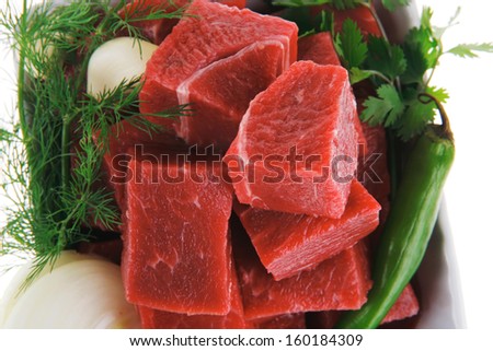 low fat slices of raw fresh beef meat fillet in a white bowls with dill and green peppers isolated over white background