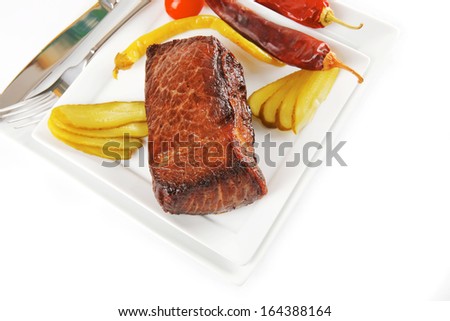 meat and peppers with knife and fork on white