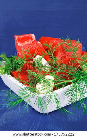 raw fresh beef meat slices in a white bowls with dill and green hot peppers serving over blue wooden table