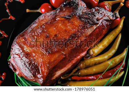 roast red beef meat bbq bloc served on black plate  with green chives and red hot pepper on black plate isolated over white background