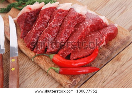 fresh raw beef meat steak\'s on wooden cut board over wooden table with dill and stainless steel knife