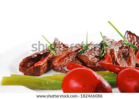 grilled red beef meat rolls with asparagus and hot spices on china plate isolated over white background