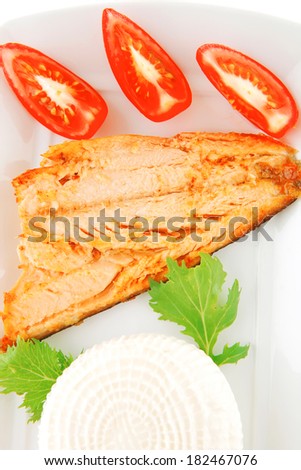 soft goat feta salt cheese with grilled sea salmon tomatoes and green lettuce salad served on white china plate isolated on white background