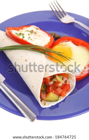 fried eggs and tortilla with salad served on blue plate with cutlery isolated over white background