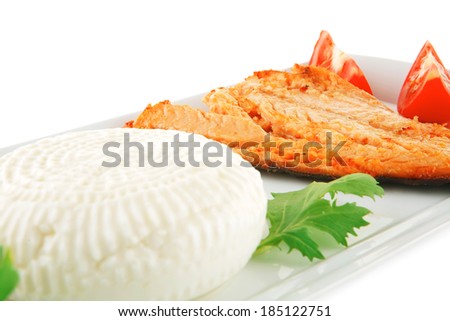soft goat feta salt cheese with grilled sea salmon tomatoes and green lettuce salad served on white china plate isolated on white background