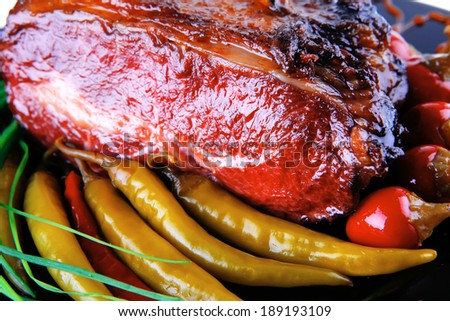 roast red beef meat bbq bloc served on black plate  with green chives and red hot pepper on black plate isolated over white background