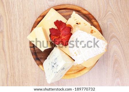 edam parmesan and brie cheese on wooden platter over wooden table