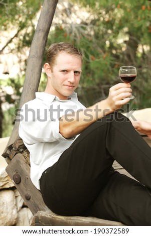 young happy white caucasion man taste and enjoy red wine outdoor in in countryside . classic style fashion.