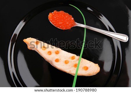 savory fish : norwegian salmon fillet roasted with green onion pen , red caviar in spoon , on black dish isolated over white background