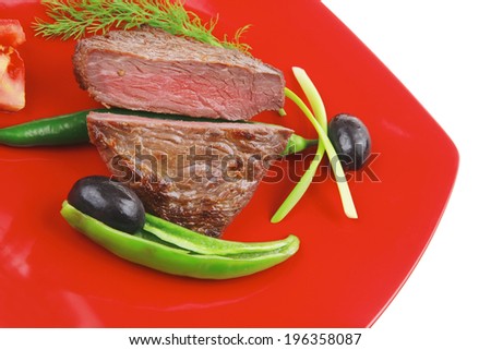 meat food : roast beef fillet mignon served on red plate with apples dill and tomatoes isolated over white background