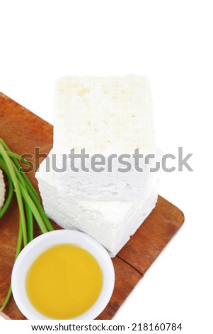 dairy product : fresh raw white soft greek feta cheese cubes and round on wooden plate isolated over white background