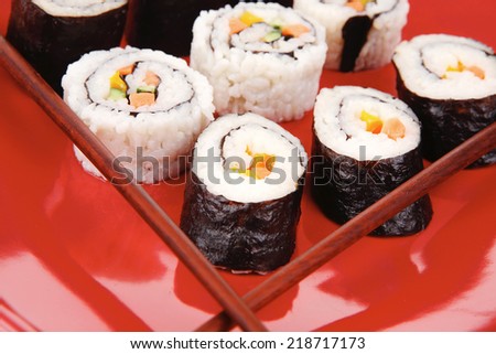 Maki Sushi : Maki Rolls and California rolls made of fresh raw Salmon, Tuna and Eel . on red dish with sticks isolated over white background