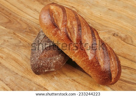 different rye and white flour french bread loaf with on light wooden table background