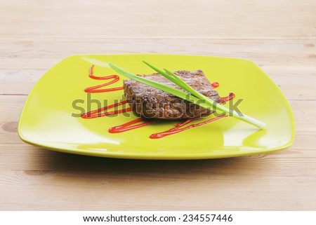 meat savory : grilled beef fillet mignon served on green plate over wooden table with chives and ketchup