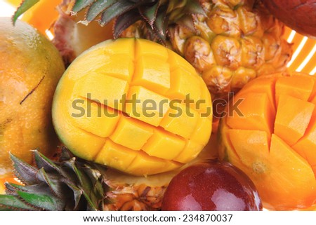 diet food - set of lot of tropical fruits include pineapple plum and mango in orange colander isolated over white background