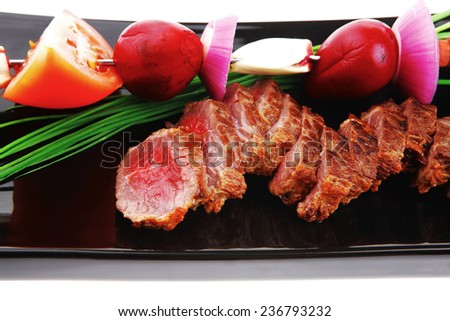 meat food : grilled fat meat served on black plate with vegetables on spit isolated on white background