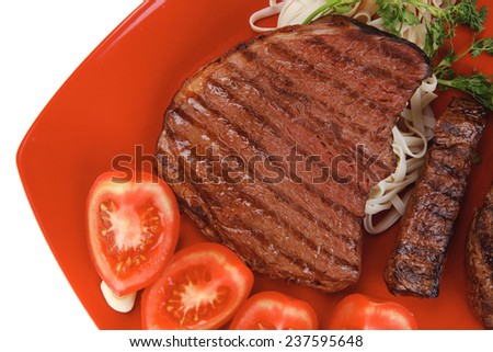 italian food : pasta with tomato and grilled sirloin beef on red plate isolated over white background