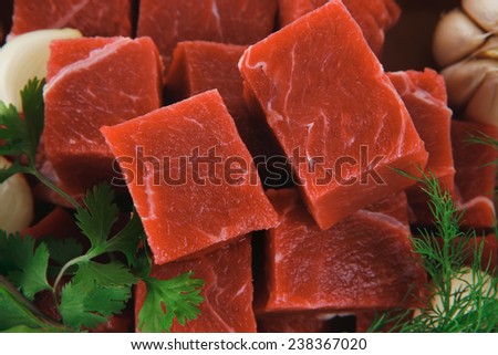slices of raw fresh beef meat fillet in a ceramic dish with onions and peppers isolated over white background