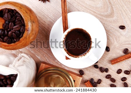 sweet hot drink : black arabic coffee in small white cup with mortar and pestle , bag full beans, copper old style cezve , decorated with cinnamon sticks and anise stars