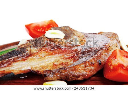 fresh hot roasted beef meat bone steak on red wooden plate with red hot pepper and capers isolated over white background
