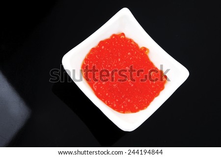 sea food : red salty salmon caviar canape isolated over black/gray background in small white bowl