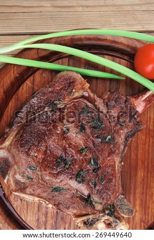 served main course: grilled pork ribs served with green chives and cherry tomato on wooden plate