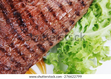 meat food : roast steak boneless with roast onion, served on green lettuce salad on dish isolated over white background