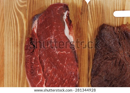 grilled and raw beef steak fillet meat on wooden board isolated over white background