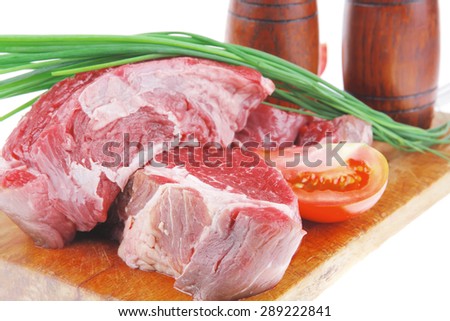 main course : fresh raw beef steak entrecote ready to prepare on cut board with green chives and tomatoes isolated on white background
