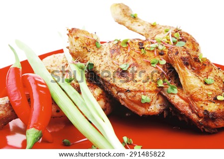 savory food : roasted chicken legs garnished with green sprouts and peppers on red plate isolated over white background