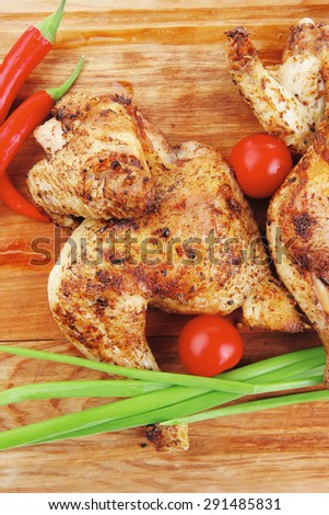 grilled meat : chicken quarters garnished with green sprouts and red peppers on wooden plate isolated over white background