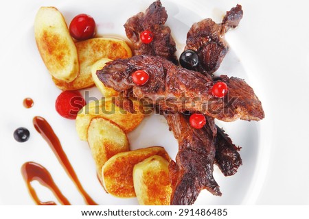 grilled beef meat with berries fried potatoes and cherry under sweet honey sauce on white plate isolated over white background