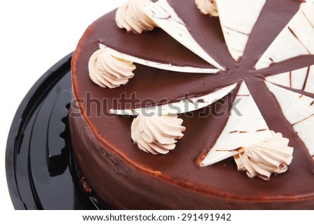 chocolate cream brownie cake topped with white chocolate slice and cream flowers on black plate isolated over white background