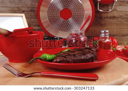 red theme lunch fresh grilled bbq roast beef steak red plate green chili tomato soup ketchup sauce paprika small jug glass ground pepper american modern cutlery wooden table empty nameplate menu board