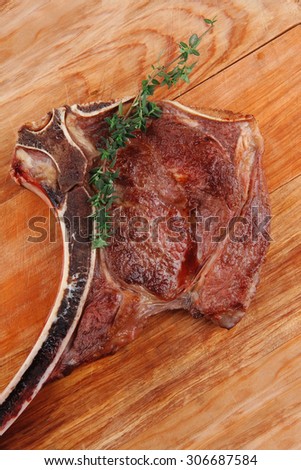 savory : roasted beef spare rib on wooden plate with cutlery and thyme