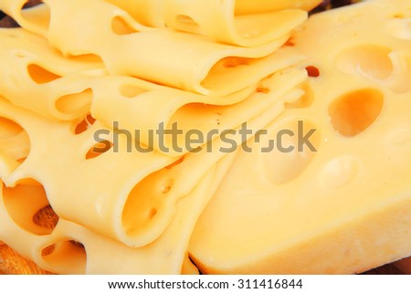 yellow edam cheese sliced on wooden platter with olives and tomato isolated over white background