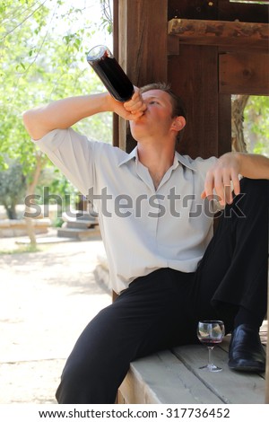 young happy white Caucasian man taste and enjoy red wine outdoor in in countryside . classic style fashion.