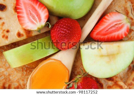 baked and fruits : pancake with honey strawberries and apple isolated over white background on wooden plate
