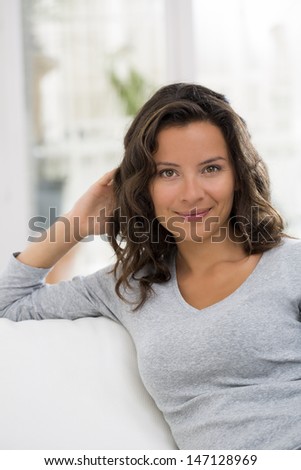 Portrait of pretty brunette woman at home on sofa