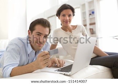 Couple using credit card to shop on line. Laptop.indoor on sofa