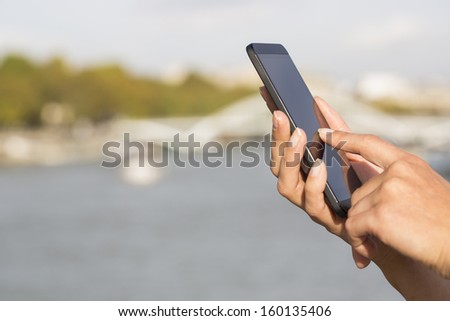 Woman in Paris using her cell phone in front of the seine, houseboat, bridge, message sms e-mail