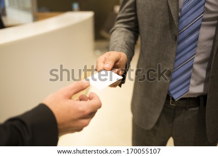 Close-up of two successful business executives exchanging a business card.